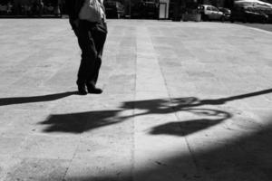 Siciliaans Mens in een plein met zijn handen in zijn zakken met langwerpig schaduw in zwart en wit Zwart en wit. schaduw en licht, Mens silhouet foto