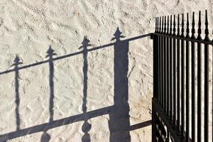 bewerkt ijzer hek en haar schaduw weerspiegeld Aan de muur. horizontaal afbeelding. foto