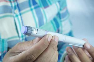gedeeltelijk wazig afbeelding van Mens Holding insuline pen. medisch uitrusting is gemakkelijk naar zelf injectie foto