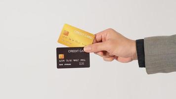 de hand- is Holding twee credit kaarten en vervelend pak. zwart en goud kleur kaarten Aan wit achtergrond. foto