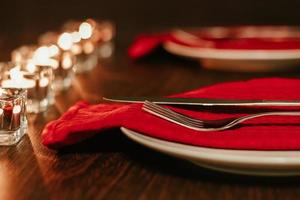 Kerstmis tafel instelling. bord en bestek Aan servet. voorbereidingen treffen voor feestelijk diner. kaarsen brandend Aan tafel Aan Kerstmis vooravond. foto