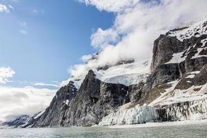 een gletsjer met sneeuw afgedekt bergen achter in Spitsbergen foto