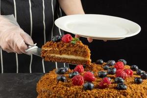 een vrouw chef bakt en eet een stuk van eigengemaakt wortel taart Aan een donker achtergrond foto