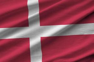 Denemarken vlag met groot vouwen golvend dichtbij omhoog onder de studio licht binnenshuis. de officieel symbolen en kleuren in banier foto