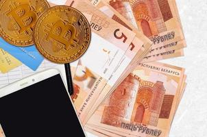 5 Wit-Russisch roebel rekeningen en gouden bitcoins met smartphone en credit kaarten. cryptogeld investering concept. crypto mijnbouw of handel foto