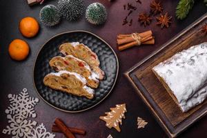 Kerstmis taart stollen met marsepein, bessen en noten Aan een donker beton achtergrond foto