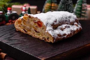 Kerstmis taart stollen met marsepein, bessen en noten Aan een donker beton achtergrond foto