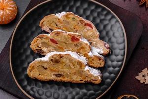 Kerstmis taart stollen met marsepein, bessen en noten Aan een donker beton achtergrond foto