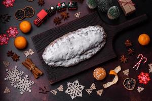 Kerstmis taart stollen met marsepein, bessen en noten Aan een donker beton achtergrond foto