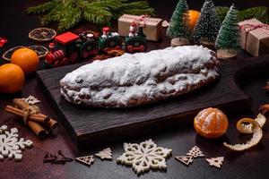 Kerstmis taart stollen met marsepein, bessen en noten Aan een donker beton achtergrond foto