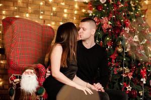 vrolijk Kerstmis en gelukkig vakantie passie paar in liefde hebben plezier, knuffelen zoenen in de buurt Kerstmis boom. liefhebbend gelukkig familie met presenteert in versierd kamer interieur foto