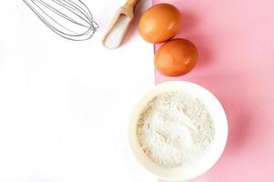 ingrediënten voor Koken bakken - meel, ei, suiker, rollend pin Aan roze achtergrond. concept van Koken nagerecht. foto