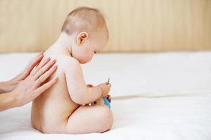 moeder en baby. gelukkig familie. mama's liefde en tederheid. moeder masseren baby in de bed Bij huis foto