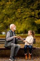 opa spelen rood handen meppen spel met zijn kleindochter in park Aan herfst dag foto