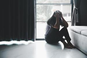 schizofrenie met eenzaam en verdrietig in mentaal Gezondheid depressie concept. depressief vrouw zittend tegen verdieping Bij huis met donker kamer gevoel miserabel. Dames zijn depressief, angstig en ongelukkig. foto