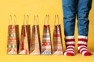 levering Kerstmis cadeaus boodschappen doen ambacht papier Tassen presenteert en kind in gebreid sokken geïsoleerd geel achtergrond verrassing voor kinderen foto