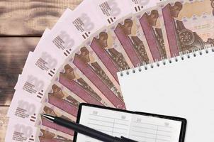 100 Russisch roebel rekeningen ventilator en kladblok met contact boek en zwart pen. concept van financieel planning en bedrijf strategie foto