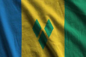 heilige vincent en de grenadines vlag met groot vouwen golvend dichtbij omhoog onder de studio licht binnenshuis. de officieel symbolen en kleuren in banier foto