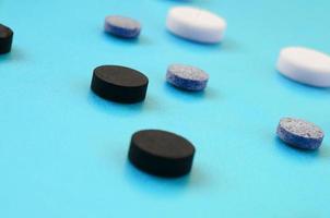 een veel van wit, zwart en grijs tablets liggen Aan de blauw oppervlak. achtergrond beeld Aan medisch en farmaceutisch topics foto