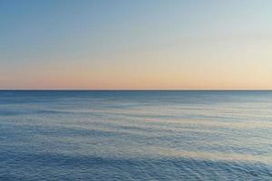 de horizon verdelen de zee en de lucht in Gelijk onderdelen Bij zonsondergang. foto