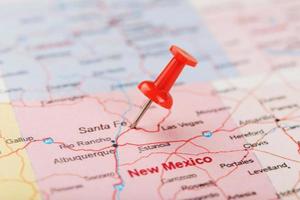 rood klerikaal naald- Aan een kaart van Verenigde Staten van Amerika, nieuw Mexico en de hoofdstad van de kerstman bijv. dichtbij omhoog kaart van nieuw Mexico met rood tack foto