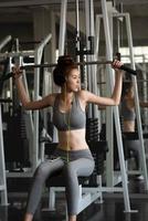 portret jong Aziatisch gezond en glimlachen vrouw training in een geschiktheid Sportschool met gewicht lifing apparatuur. foto