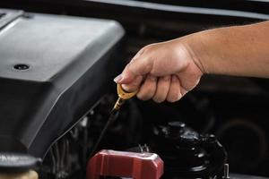 Mens hand- trekken olie peilen stok omhoog voor controle niveau van motor olie smeermiddel in de motor, auto onderhoud onderhoud concept. foto