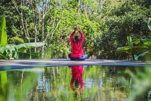 jonge vrouw reizen natuur ze staande oefening bij het zwembad ontspannen, reflecties van aziatische vrouw op het wateroppervlak. foto