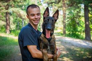 jong Kaukasisch hipster besteedt tijd met zijn hond in de park Aan een zonnig zomer dag. de concept van een huisdier net zo een familie lid foto