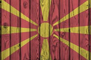 Macedonië vlag afgebeeld in helder verf kleuren Aan oud houten muur. getextureerde banier Aan ruw achtergrond foto