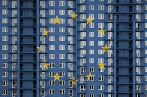 Europese unie vlag afgebeeld in verf kleuren Aan meerdere verdiepingen woonachtig gebouw onder bouw. getextureerde banier Aan steen muur achtergrond foto