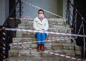 foto van een meisje in een masker. zittend Aan de straat met Gevaar waarschuwing banden.