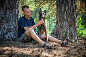 jong Kaukasisch hipster besteedt tijd met zijn hond in de park Aan een zonnig zomer dag. de concept van een huisdier net zo een familie lid foto