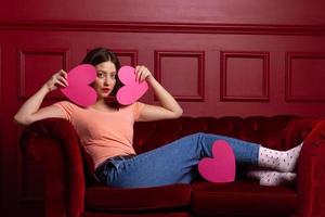 Dames Aan bankstel Holding hart vormen in voorkant van haar gezicht foto