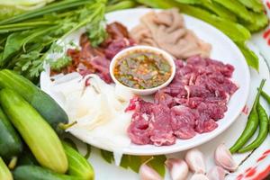 rauw rundvlees plak Aan bord met vers groenten en pittig saus, rundvlees sashimi vlees - Thais voedsel stijl pittig rauw rundvlees salade pittig fijngehakt vlees salade foto