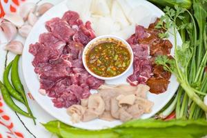 rauw rundvlees plak Aan bord met vers groenten en pittig saus, rundvlees sashimi vlees - Thais voedsel stijl pittig rauw rundvlees salade pittig fijngehakt vlees salade foto