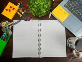 vlak leggen, een bespotten omhoog van een notebook. werkruimte in de achtergrond van de kantoor bureau van de top visie. met wit notitieboekjes, laptops, kantoor benodigdheden, potloden, en koffie cups in de houten bureau. foto