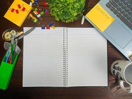 vlak leggen, een bespotten omhoog van een notebook. werkruimte in de achtergrond van de kantoor bureau van de top visie. met wit notitieboekjes, laptops, kantoor benodigdheden, potloden, en koffie cups in de houten bureau. foto