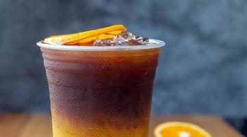 dichtbij omhoog van bevroren koffie drinken menu oranje americano fusie met vers oranje fruit gemengd in een plastic beker, drinken menu Product. foto