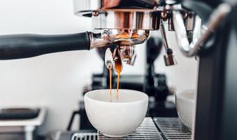 koffie extractie van de koffie machine met een filterhouder gieten koffie in een kopje, espresso poreus van koffie machine Bij koffie winkel foto