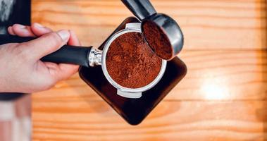 barista giet koffie Boon brander poeder grond koffie gieten in een filterhouder met een barista hand- Bij de koffie winkel foto