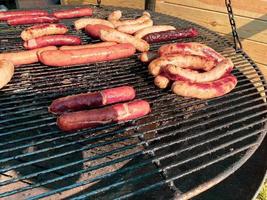 koken bereidt zich voor en bakken Aan de rooster barbecue broodjes en worstjes voor heet hond foto