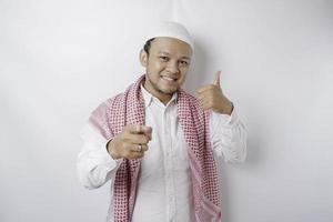 opgewonden Aziatisch moslim Mens geeft duimen omhoog hand- gebaar van goedkeuring, geïsoleerd door wit achtergrond foto