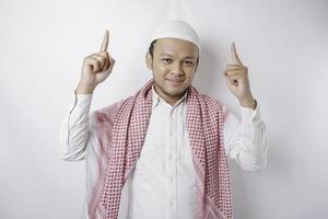 glimlachen Aziatisch moslim Mens richten Bij de kopiëren ruimte Aan top van hem, geïsoleerd door wit achtergrond foto