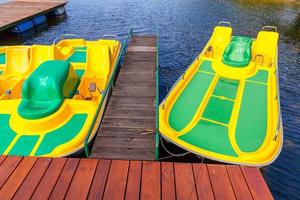 waterfietsen of waterfietsen catamarans station. gele waterfietsen vergrendeld op de pier van de jachthaven van het meer op zonnige zomerdag. zomer vrijetijdsbesteding buitenshuis. foto