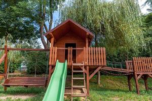 lege moderne houten kinderspeelplaats ingesteld op groene tuin in openbaar park in zomerdag. grappig speelgoedland voor kinderen. stedelijke bewegingsactiviteiten voor kinderen buitenshuis. buurt jeugd concept. foto