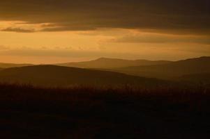 zonsondergang in natuur, oranje, lucht met wolken, veld- en bossen foto