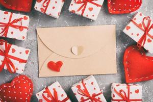 envelop mail met rood hart en geschenk doos over- grijs cement achtergrond. Valentijn dag kaart, liefde of bruiloft groet concept foto