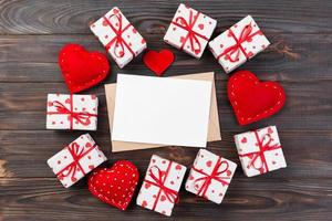 Valentijn of andere vakantie handgemaakt Cadeau in papier met rood harten en cadeaus doos in vakantie wikkel. Cadeau doos van geschenk Aan donker houten tafel top visie met kopiëren ruimte, leeg ruimte voor ontwerp foto