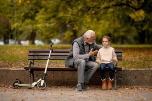 opa uitgeven tijd met zijn kleindochter Aan bank in park Aan herfst dag foto